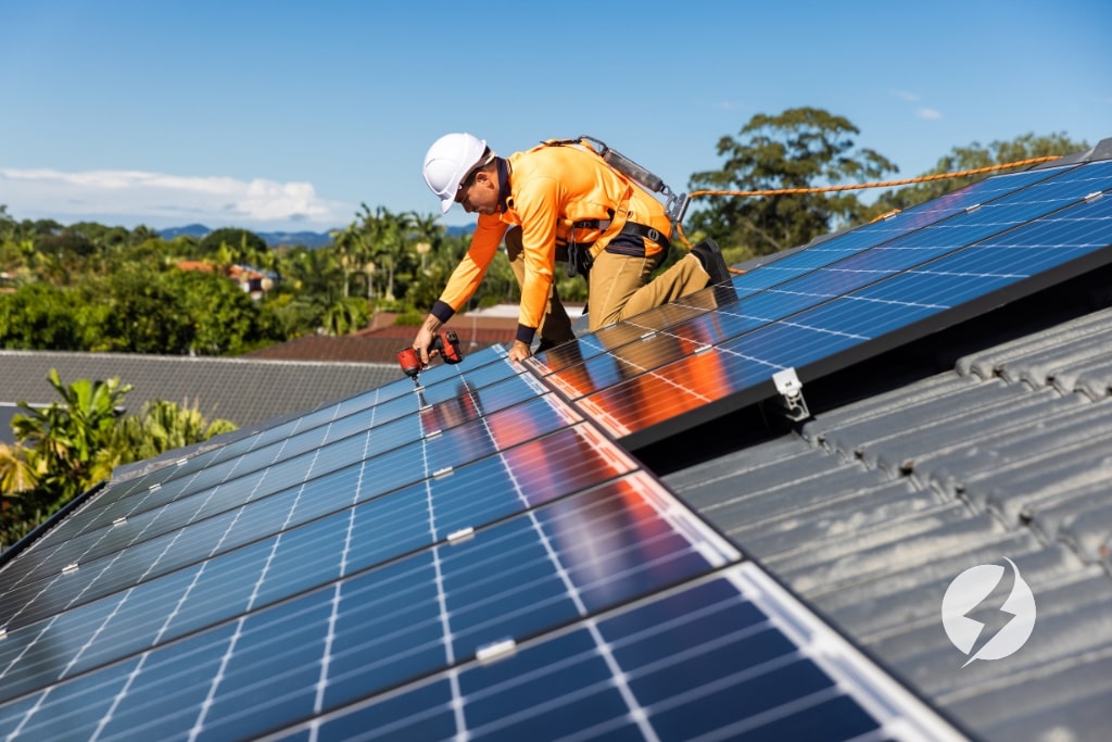 Operario instalando paneles solares en el tejado de una casa